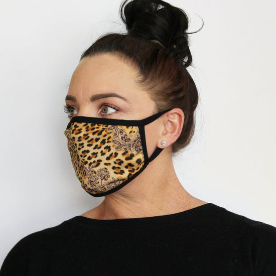 Side profile of woman wearing an ear-loop face mask with spotted animal print and black bind